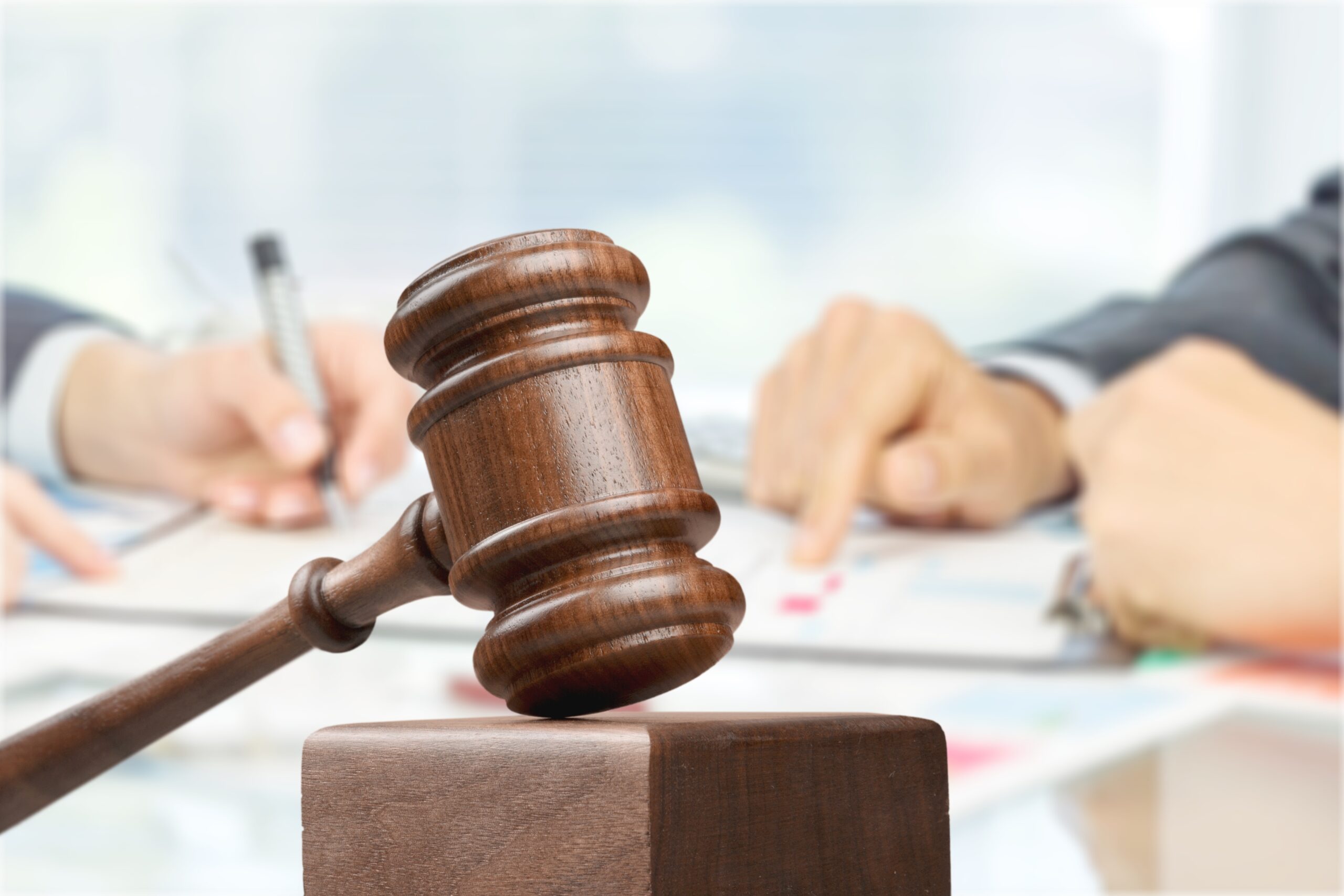 Male hands writing and wooden judge hammer on background