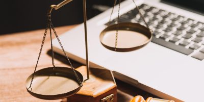 Business and lawyers discussing contract papers with brass scale on desk in office. Law, legal services, advice, justice and law concept picture with film grain effect