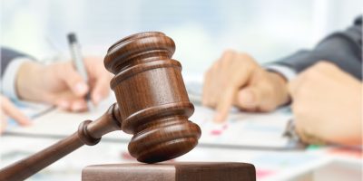 Male hands writing and wooden judge hammer on background